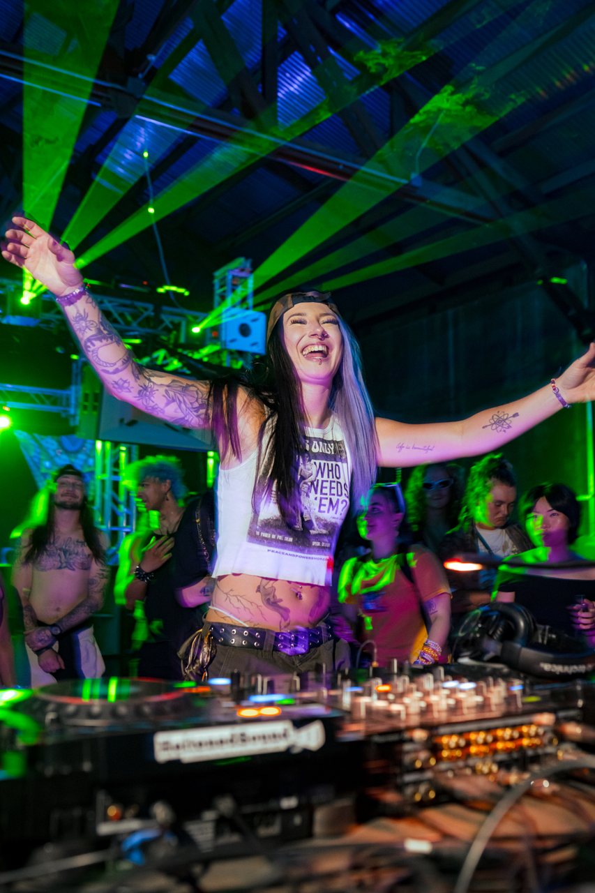 Allie Radd, arms wide to the crowd under green lasers